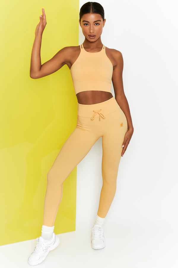 model wearing yellow tie front gym leggings with matching crop top