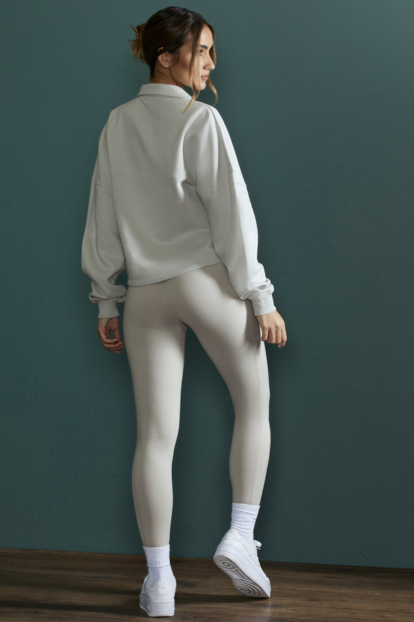 model posing to show back of matching half zip sweatshirt and leggings set