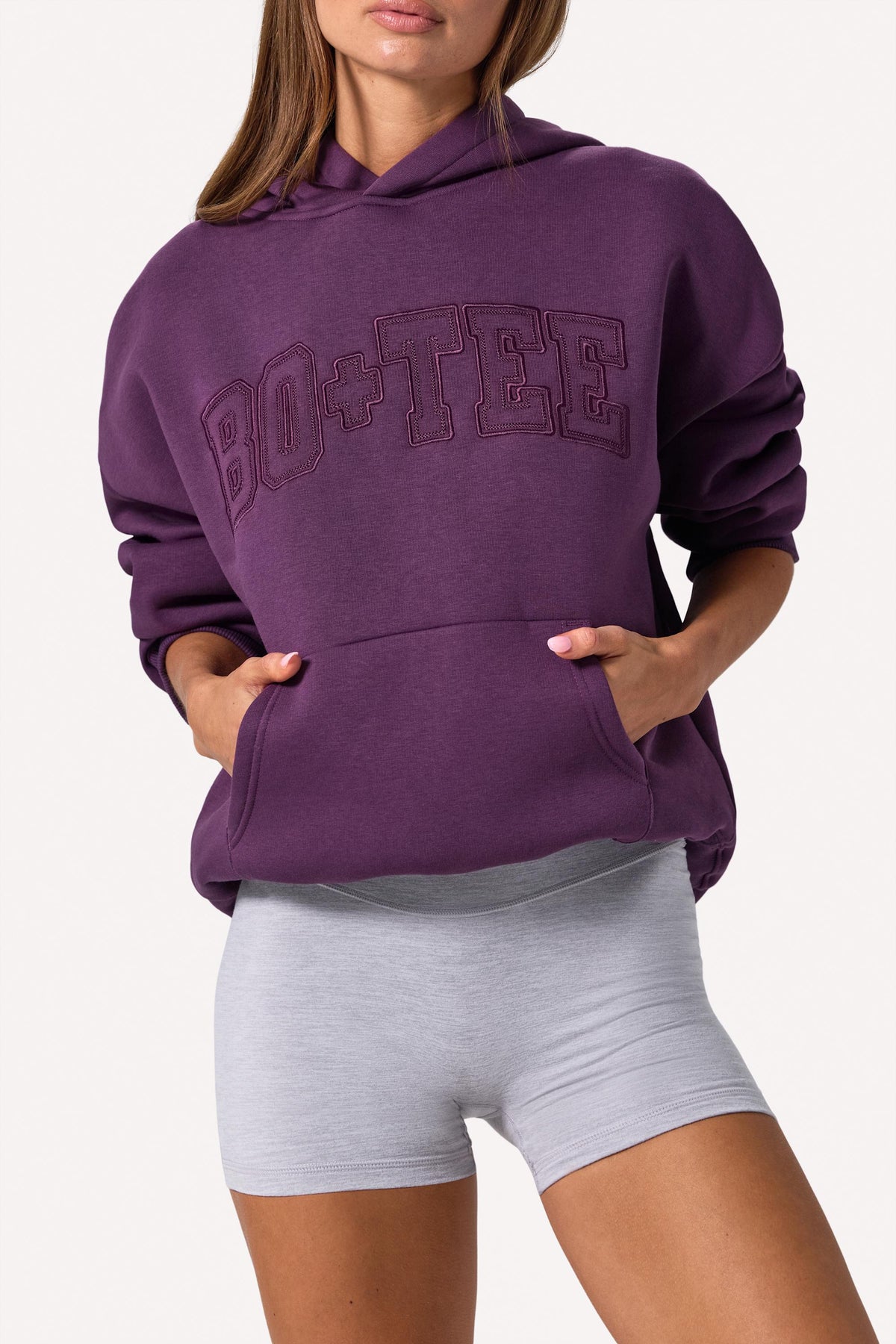 Bo+Tee model Lydia Butler wearing the CosyCoffeeRunWithLydsButler Hoodie in Plum Brushback sweat fabric perfect for cozy study sessions