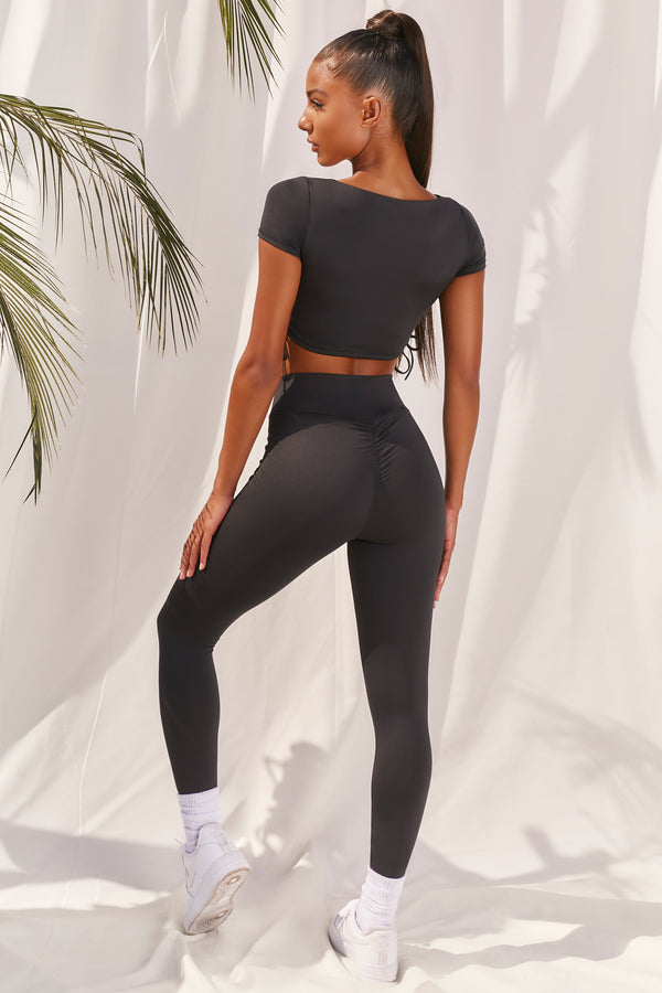 Plain black slinky high waisted full length gym leggings with rear ruched seam. Image 3 of 6.