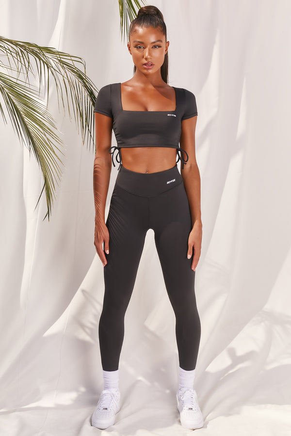 Plain black slinky high waisted full length gym leggings with rear ruched seam. Image 1 of 6.