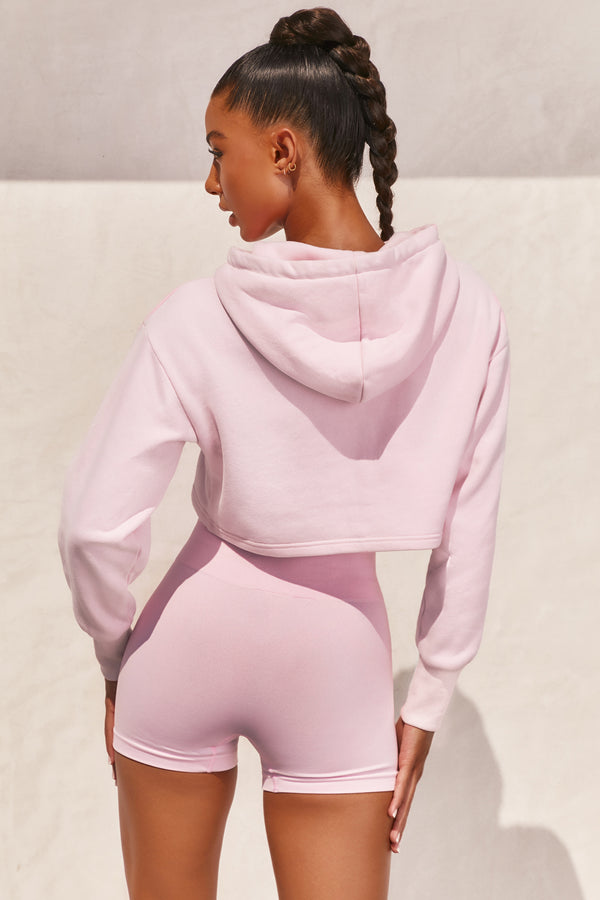 Pink long sleeved cropped hoodie with embroidered Bo+Tee logo across the chest. Image 3 of 6