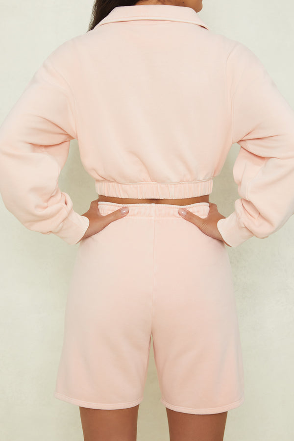 back view of matching blush shorts and long sleeve cropped sweatshirt
