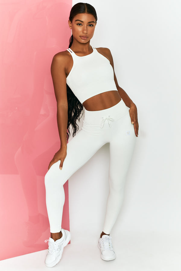 model styled in white trainers with matching gym crop top and leggings