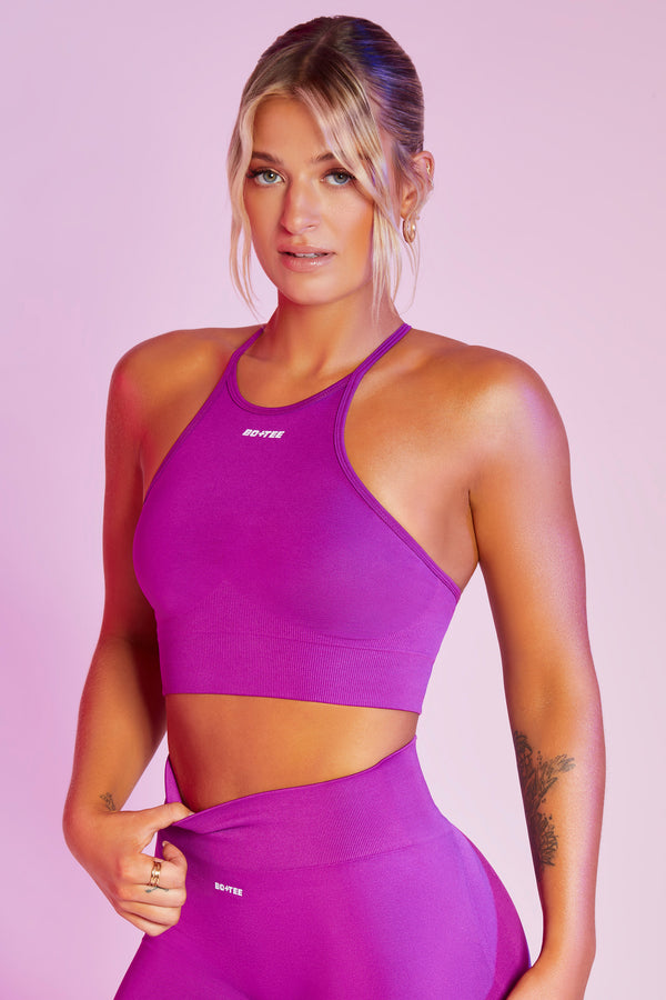model wearing purple high neck gym crop top with branded detail