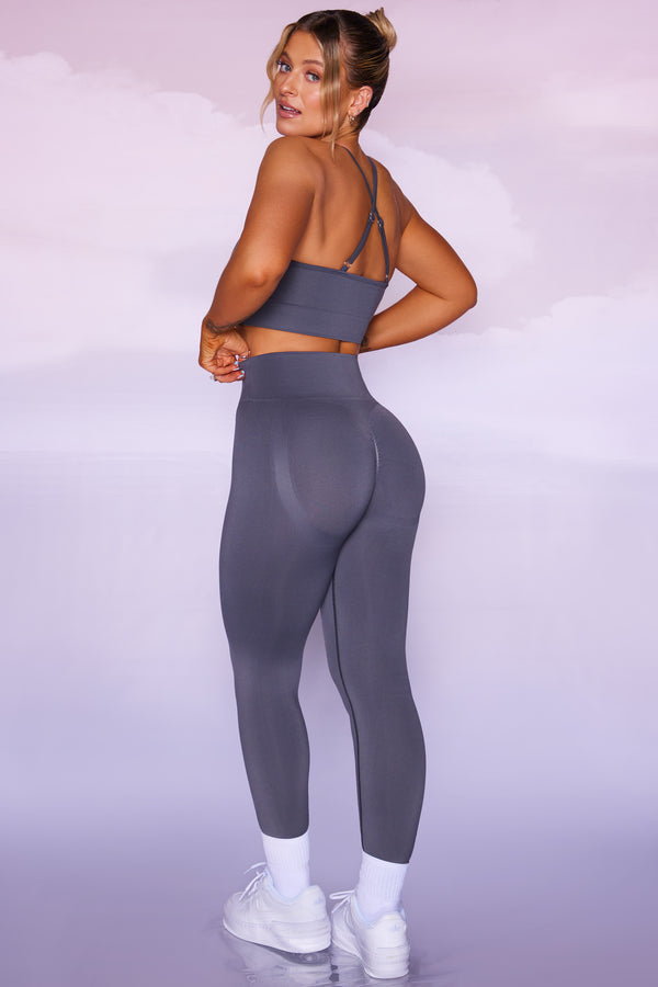 model posing to show back of seamless womens gym leggings and crop top in grey