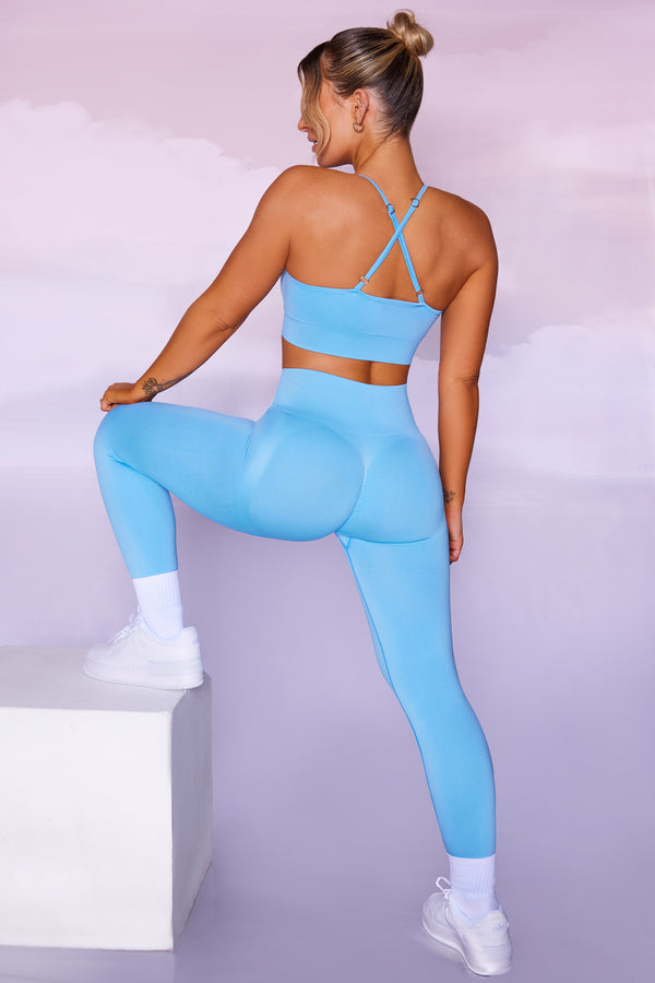 model showing back of petite seamless leggings and cross back top in blue