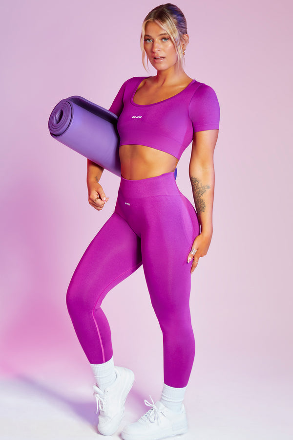 model wearing seamless and curved waist womens gym leggings and crop top in purple