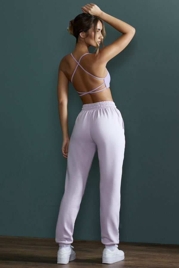 model posing to show back of cross back lilac sports bra and matching jogger bottoms