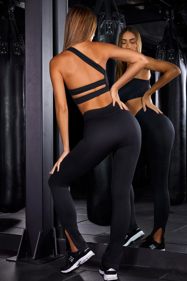 model posing to the side in high waist split flare black gym leggings and crop top