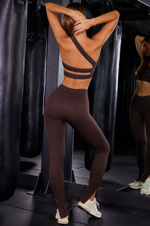 model posing to show back of brown split flare gym leggings and sports bra